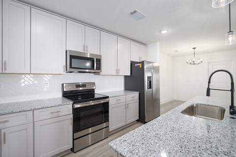 A kitchen with white cabinets and a granite countertop.