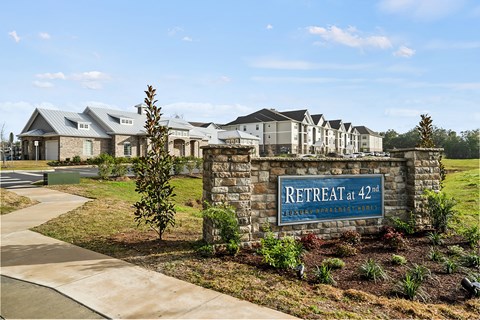 A sign that says "Retreat at 42nd" is in front of a building.