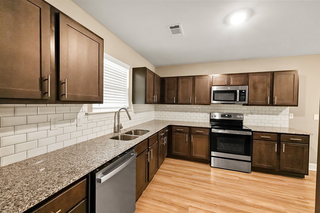 A kitchen with brown cabinets and a granite countertop.