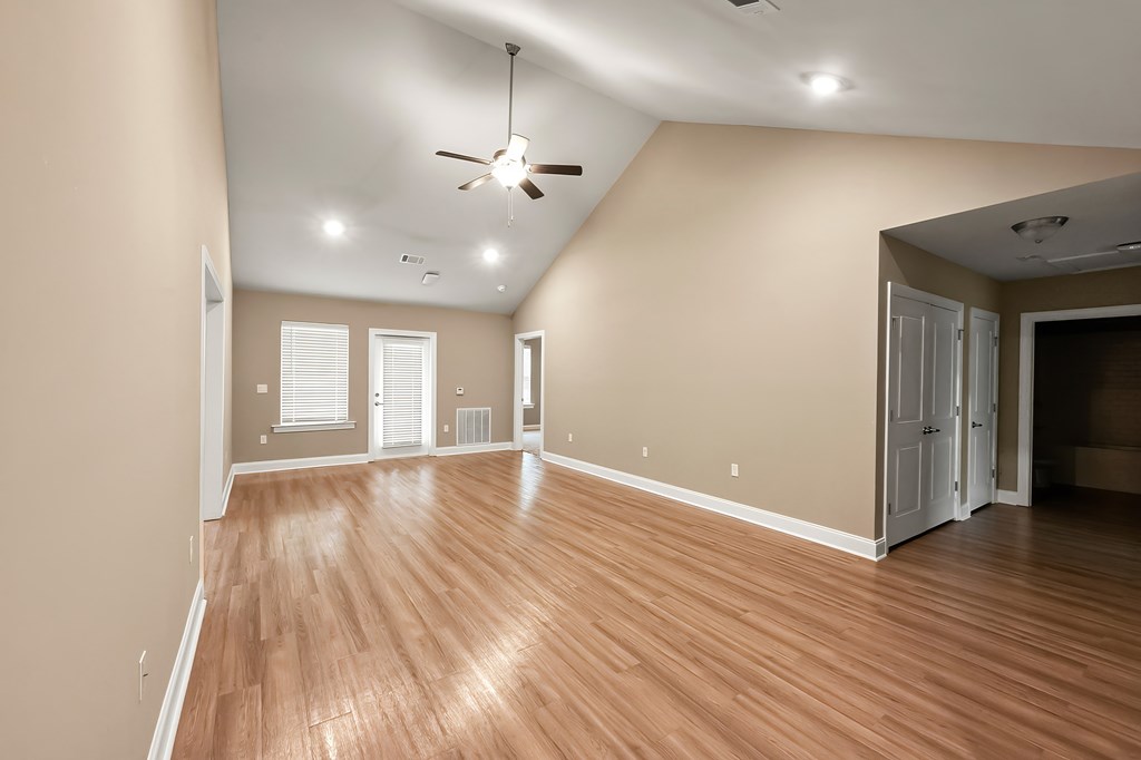 A room with a ceiling fan and wooden flooring.