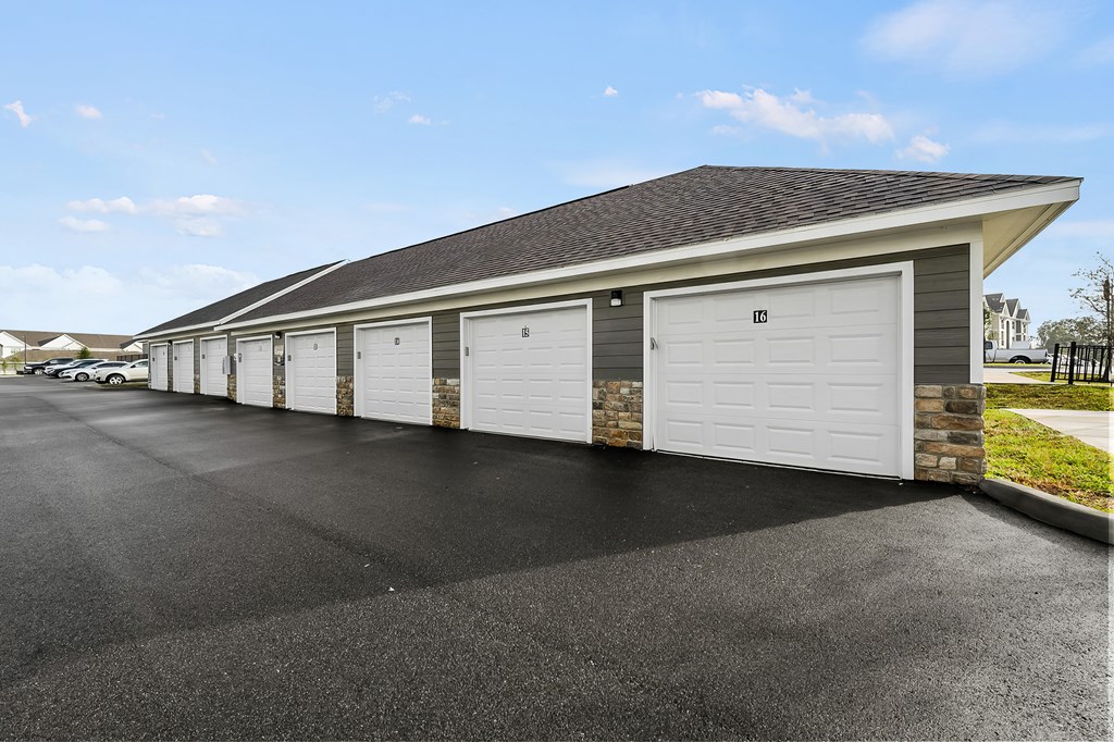 A long building with a grey roof and white garage doors.