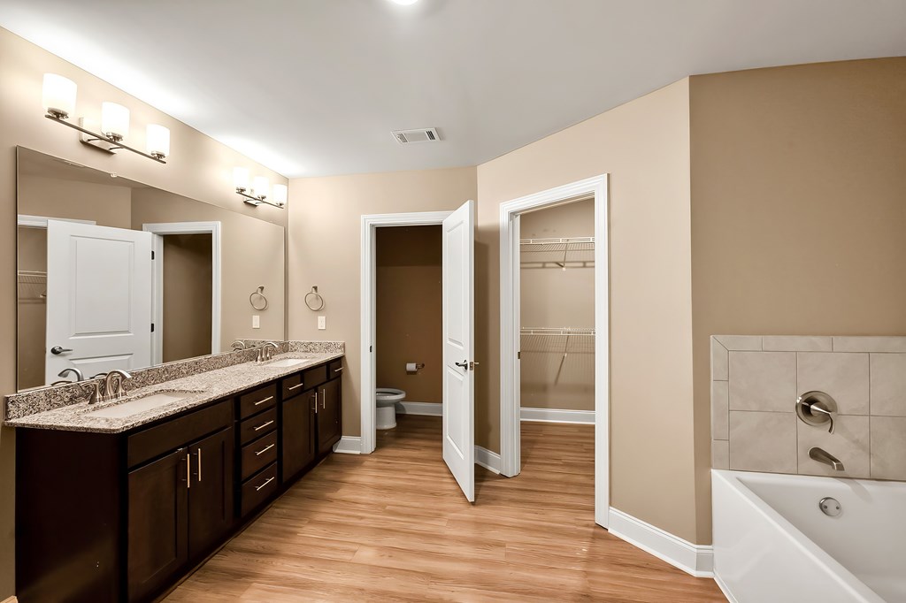 A bathroom with a brown cabinet and a white tub.