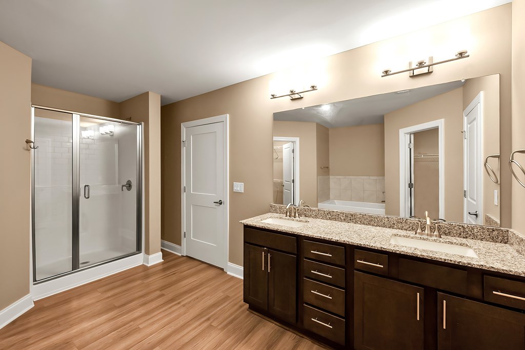 A bathroom with brown cabinets and a marble counter top.
