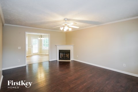 A spacious living room with a fireplace and a ceiling fan.
