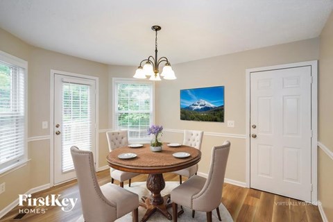 A dining room with a table set for two and a painting of a mountain scene on the wall.
