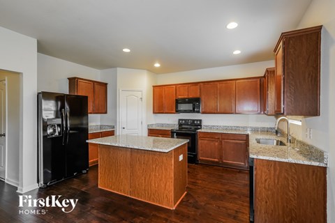 A kitchen with wooden cabinets and a black fridge.