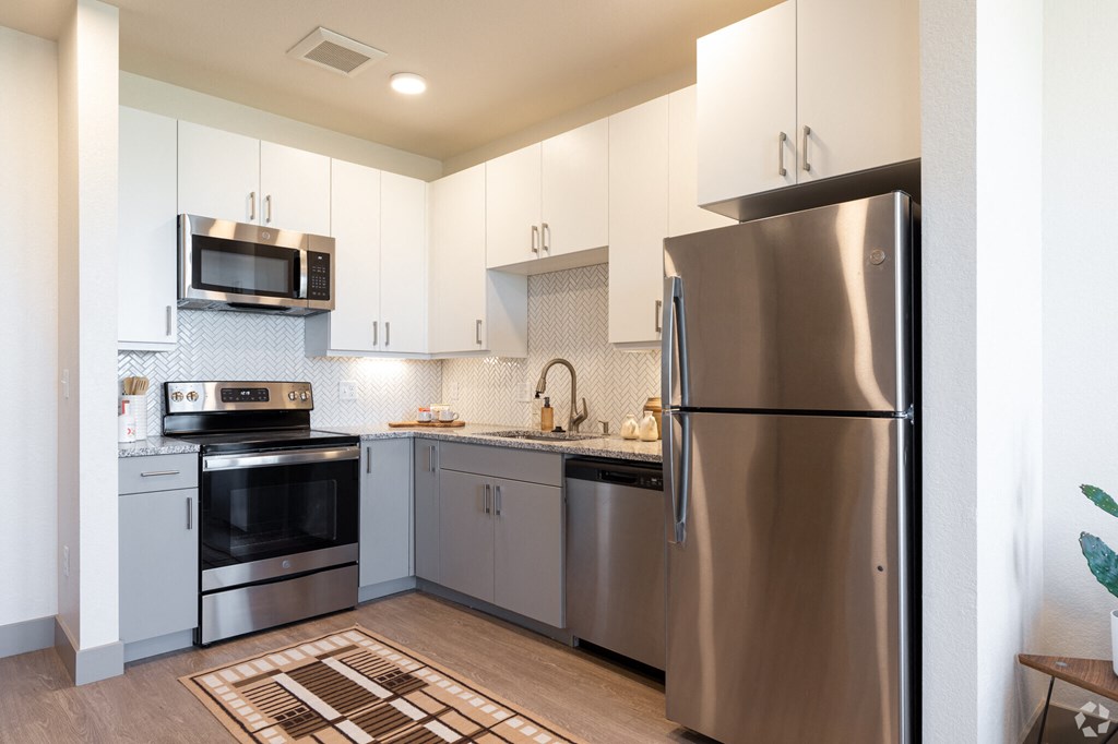 A modern kitchen with stainless steel appliances and white cabinets.
