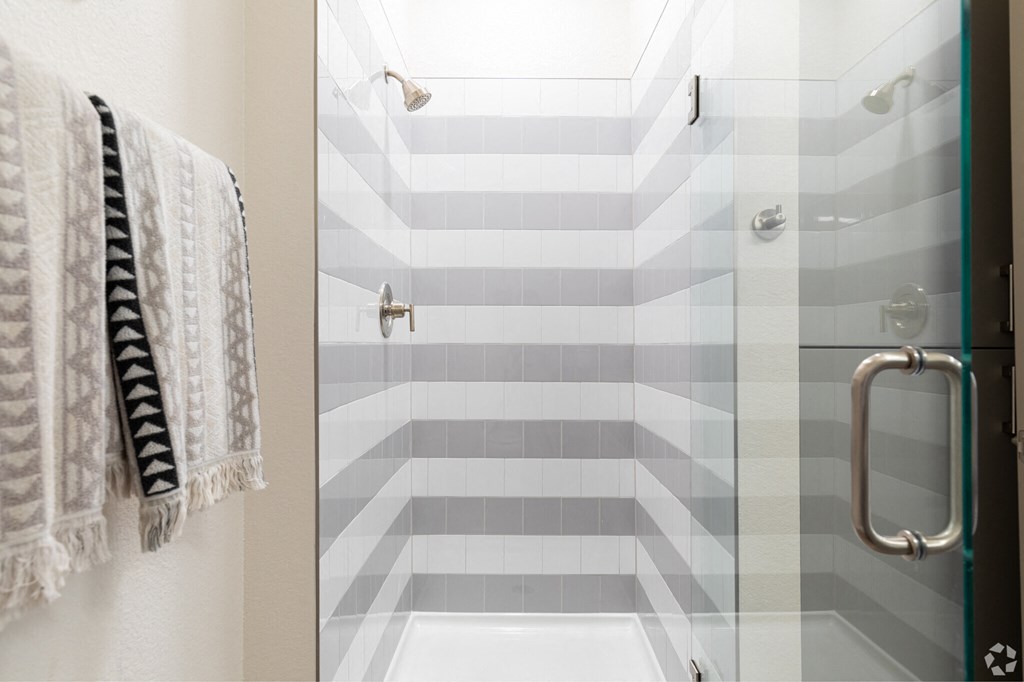 A bathroom with a striped tile shower.