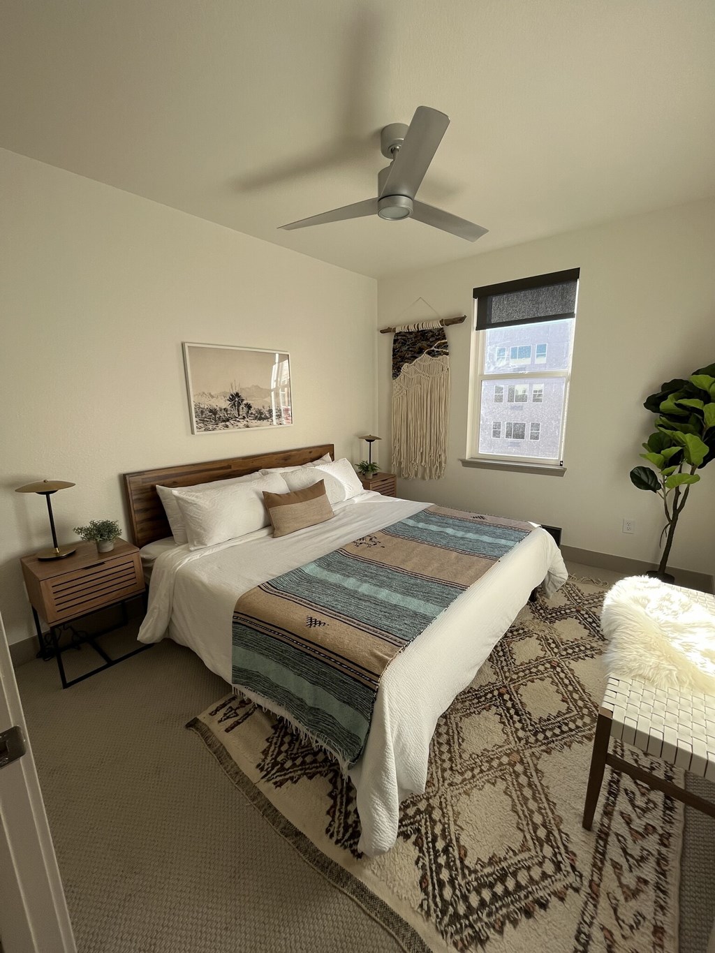 A bedroom with a bed, a fan, and a rug.