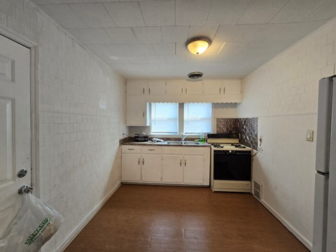 A kitchen with white cabinets and a wooden floor.