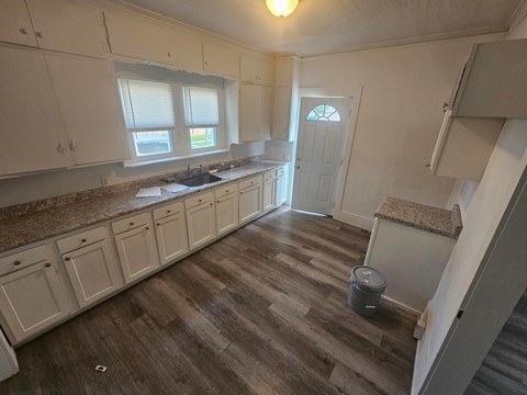 A kitchen with white cabinets and a brown counter top.