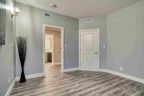 A room with a door and a vase on the floor.