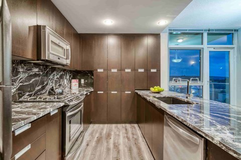 A kitchen with brown cabinets and a marble countertop.