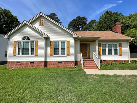 A house with a red brick base and yellow shutters.