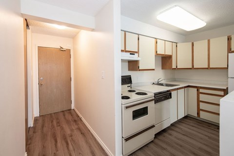 A kitchen with a stove top oven and a doorway leading to a hallway.