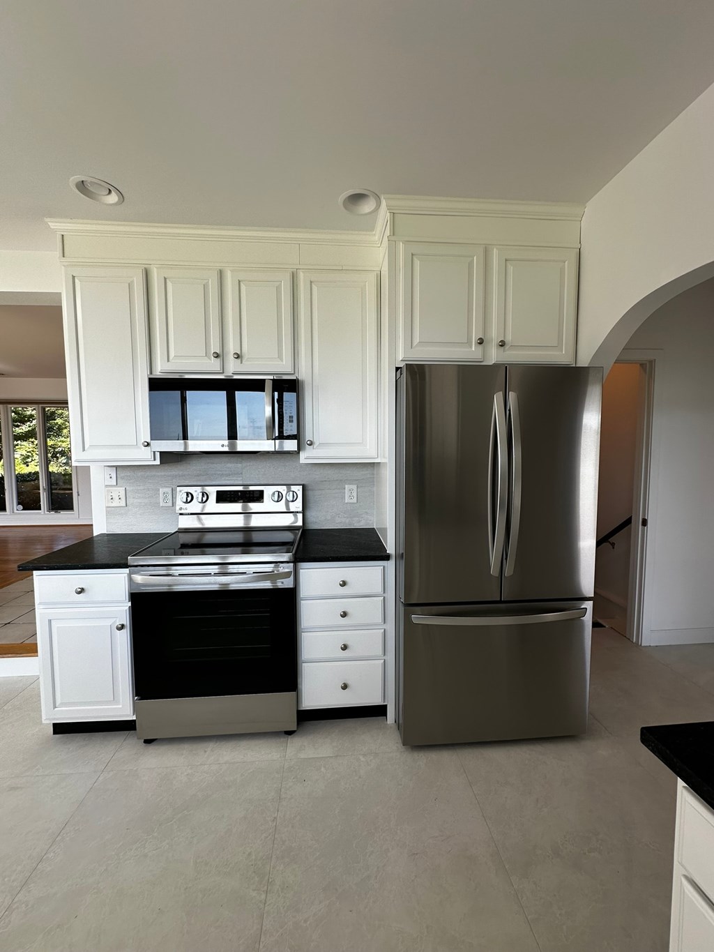 A modern kitchen with white cabinets and a stainless steel refrigerator.