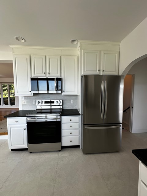 A modern kitchen with white cabinets and a stainless steel refrigerator.