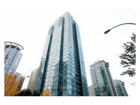 A tall glass building stands in a cityscape.