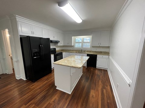 A kitchen with black appliances and white cabinets.