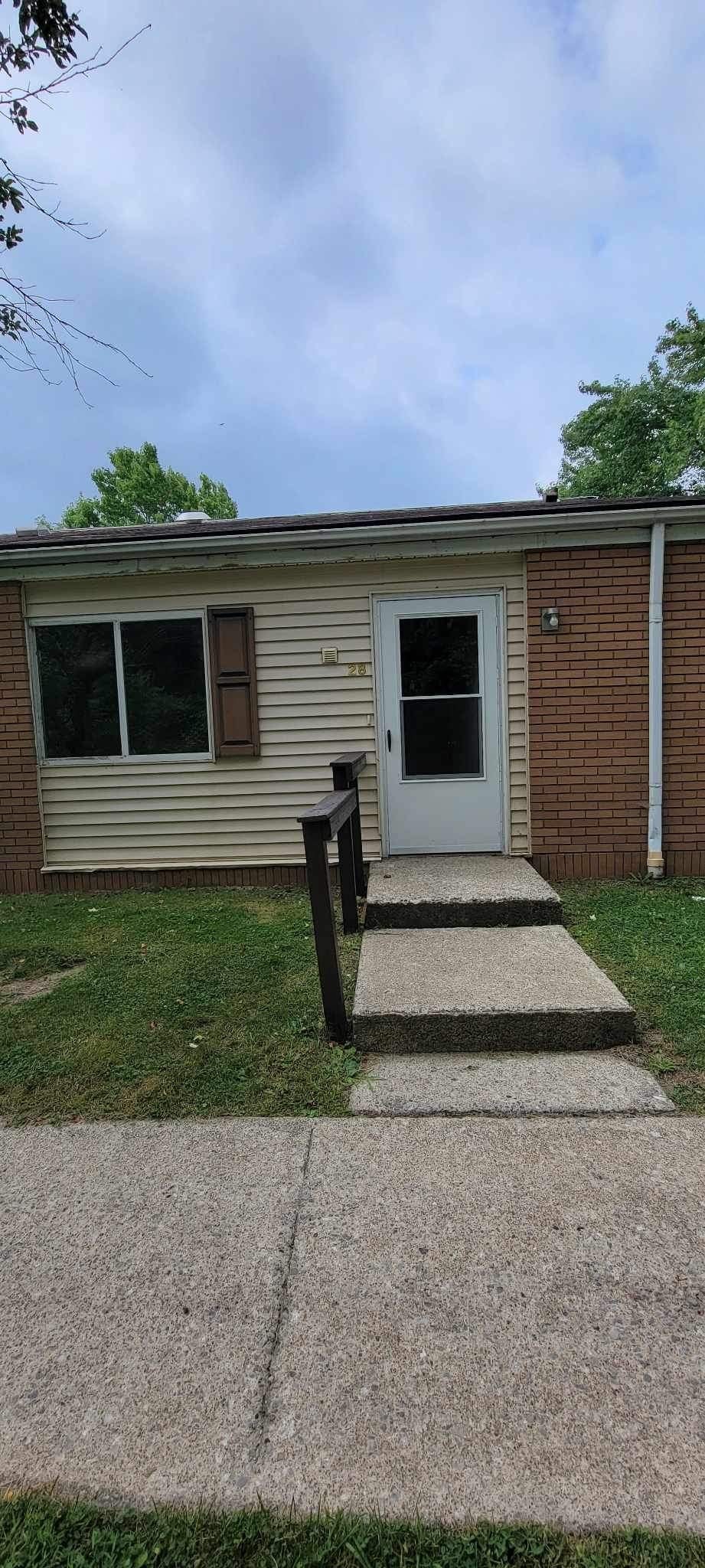 A small house with a white door and a brown roof.