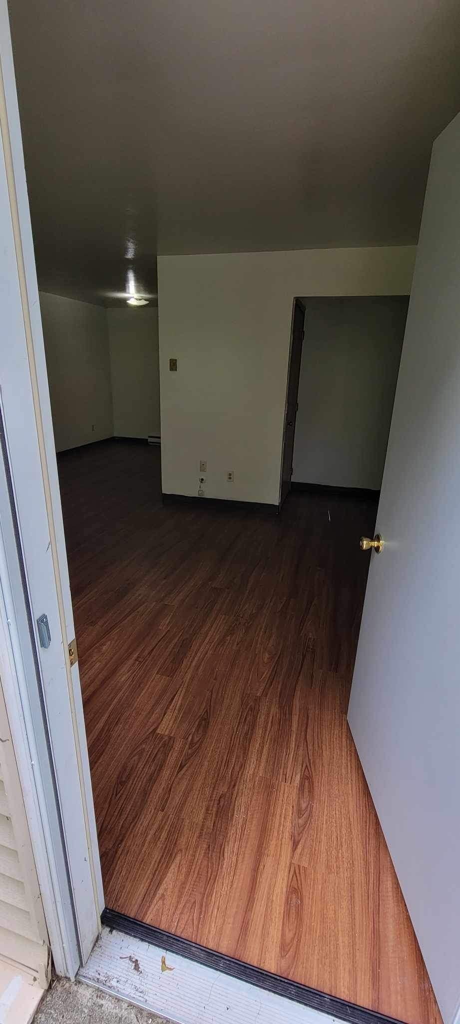 A room with wooden flooring and white walls.