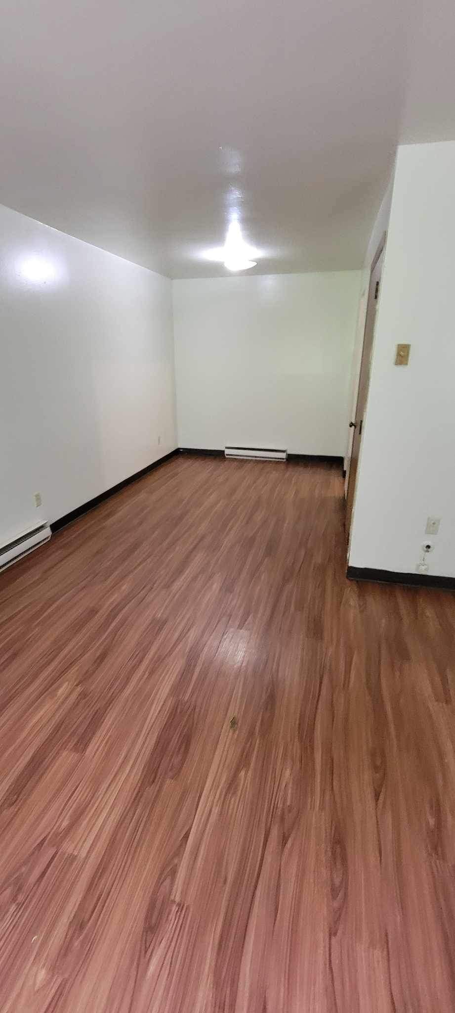 A room with wooden flooring and white walls.