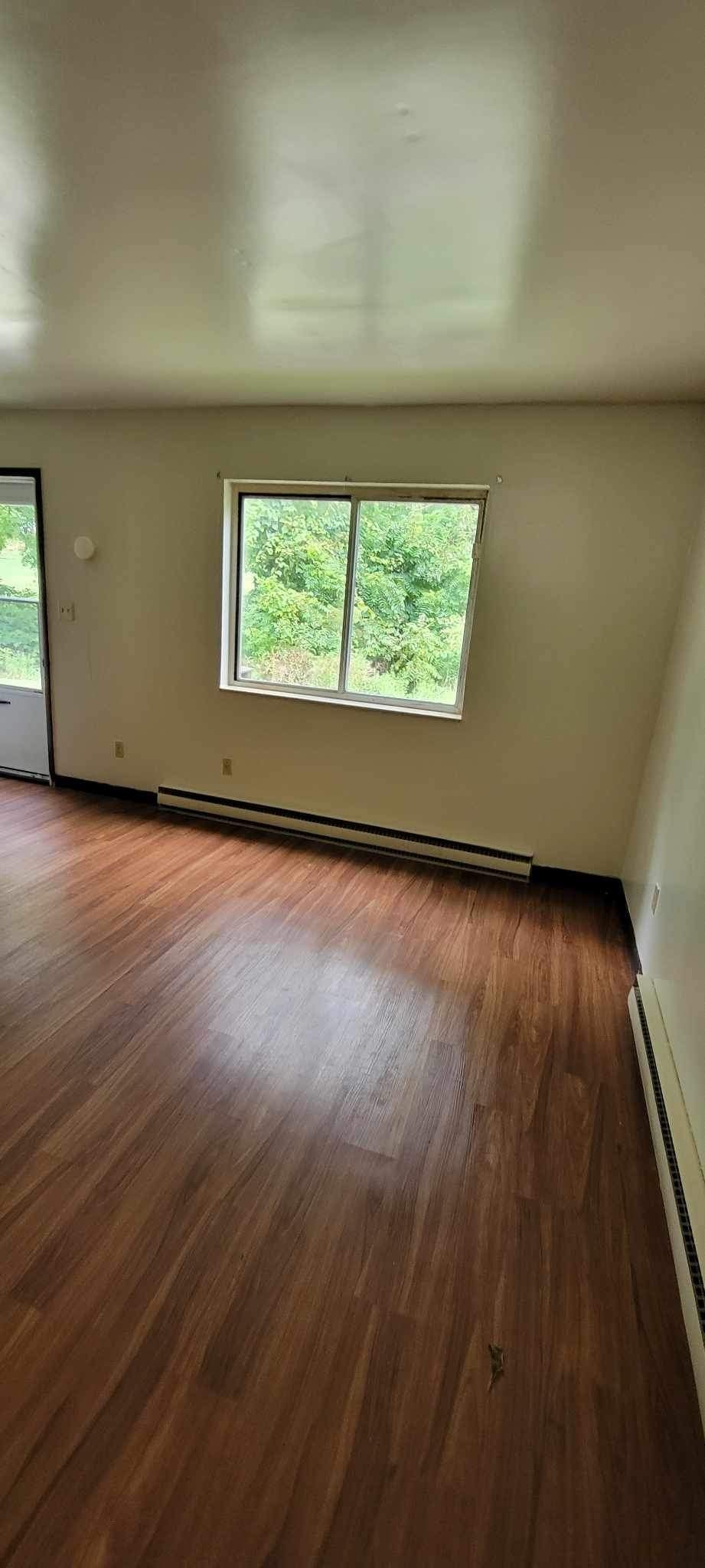 A room with a window and wooden flooring.