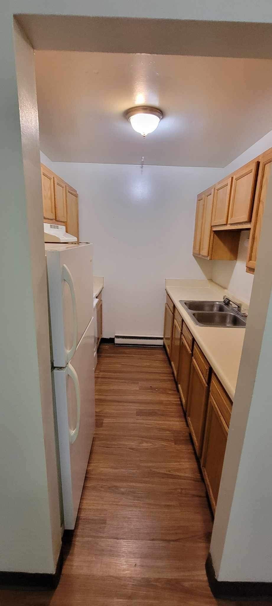A kitchen with wooden cabinets and a white refrigerator.