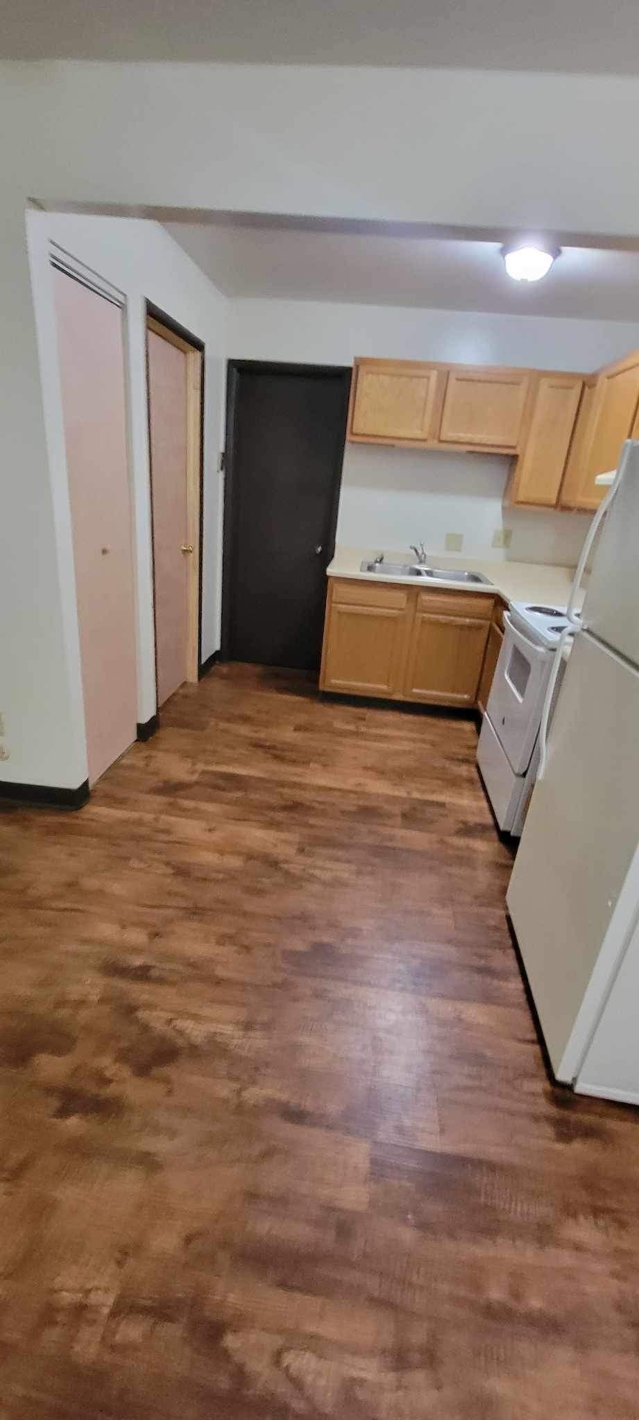 A kitchen with wooden floors and white appliances.