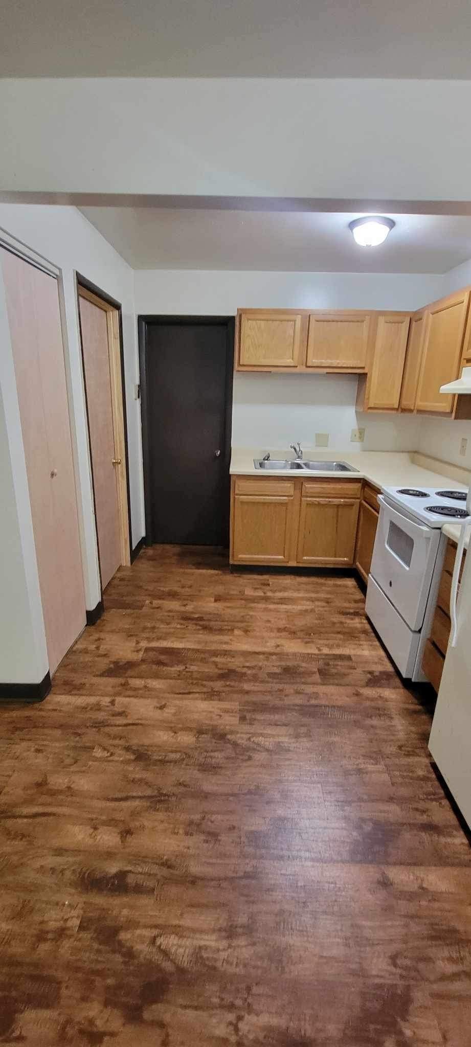 A kitchen with wooden floors and a black door.