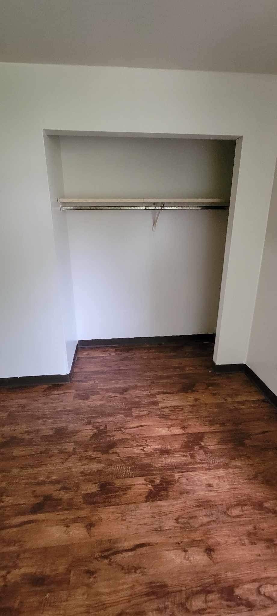 Empty room with a shelf and wooden floor.