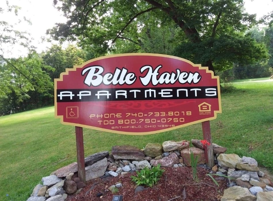 A sign for Belle Haven Apartments with a phone number and address.