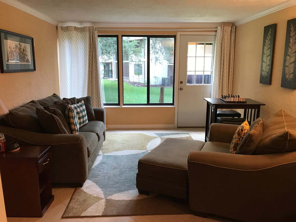 A living room with a couch, chair, and a table with a chess set on it.