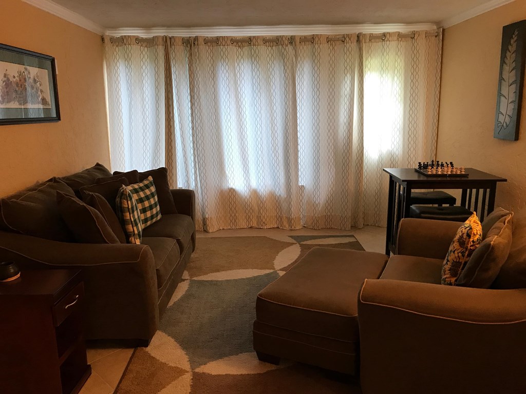 A living room with a brown couch, a chair, and a coffee table.