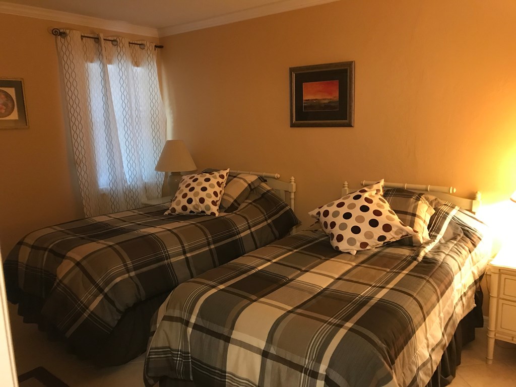 Two beds with plaid bedspreads and white pillows.