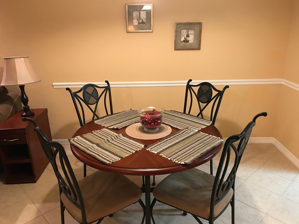 A table with chairs and a vase of flowers on top.