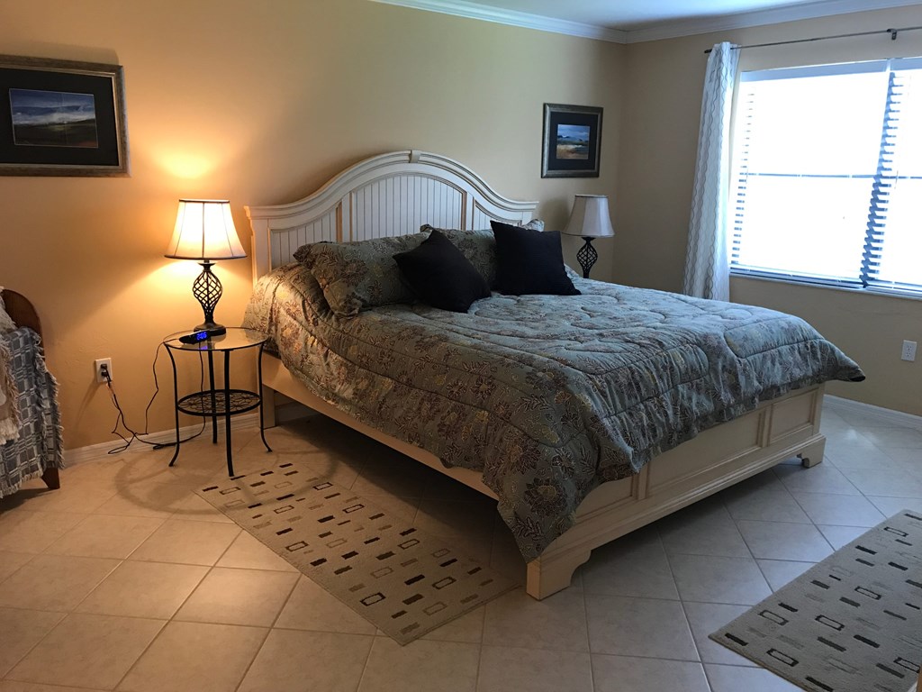 A bedroom with a large bed and two lamps.