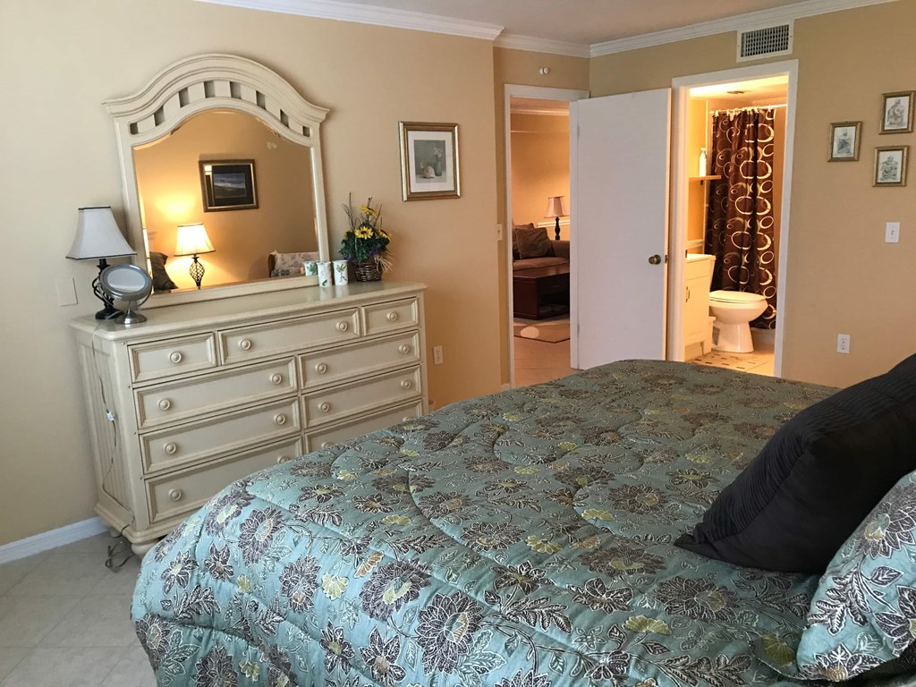 A bedroom with a bed, dresser, and mirror.