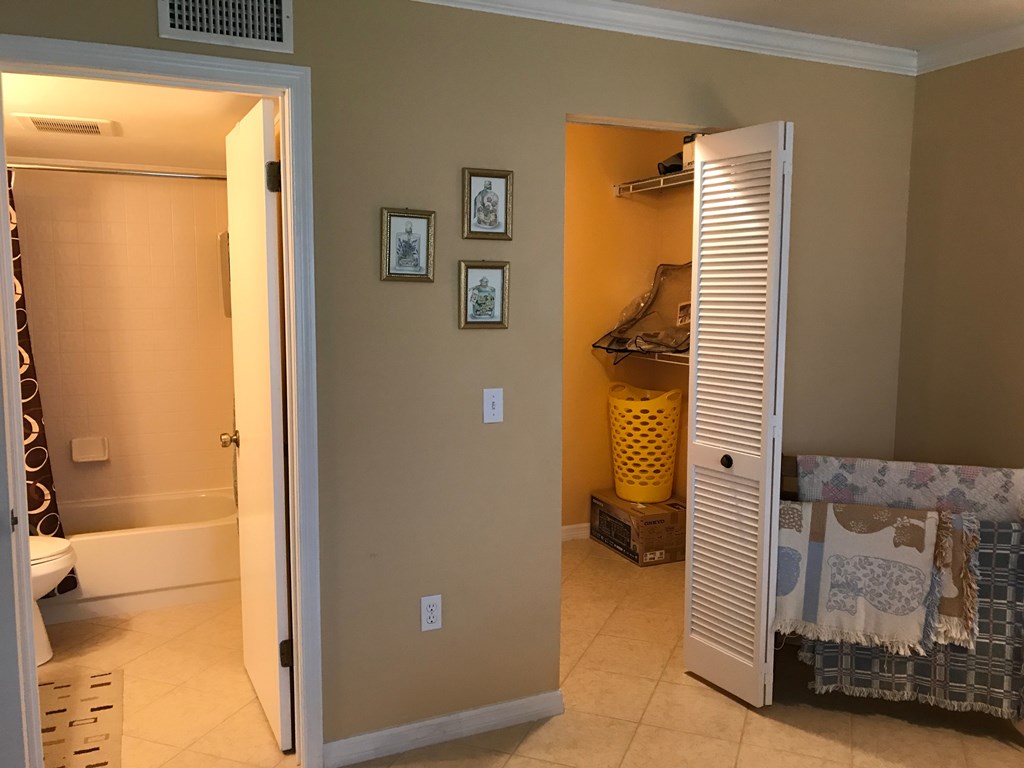 A room with a white door, a yellow bucket, and a white cabinet with a blue blanket.