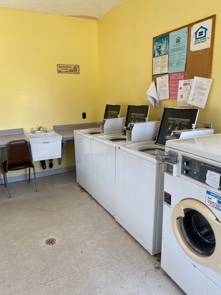 A yellow wall with a washing machine and a dryer in front of it.