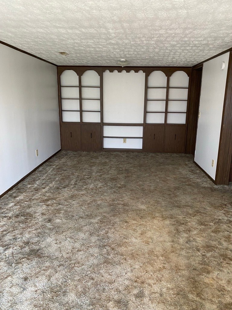 A room with a carpeted floor and a large window with wooden frames.