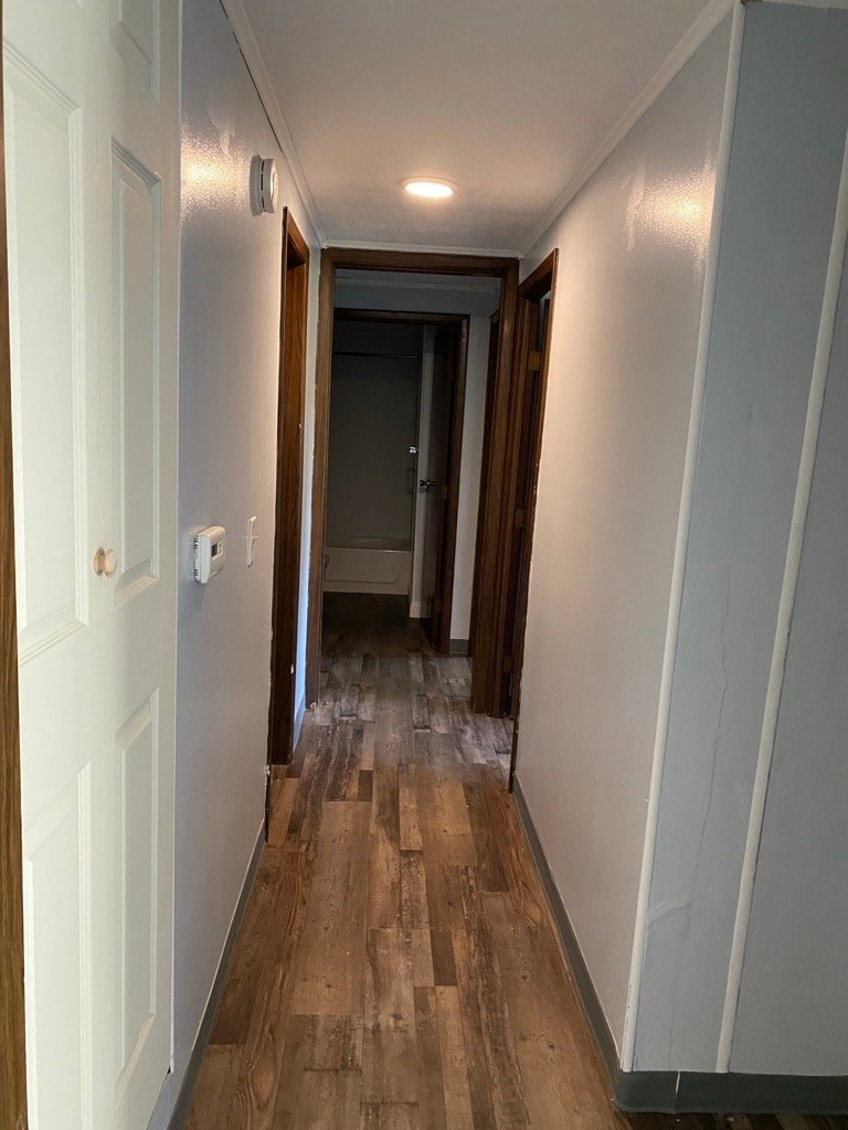 A long hallway with wood floors and white walls.