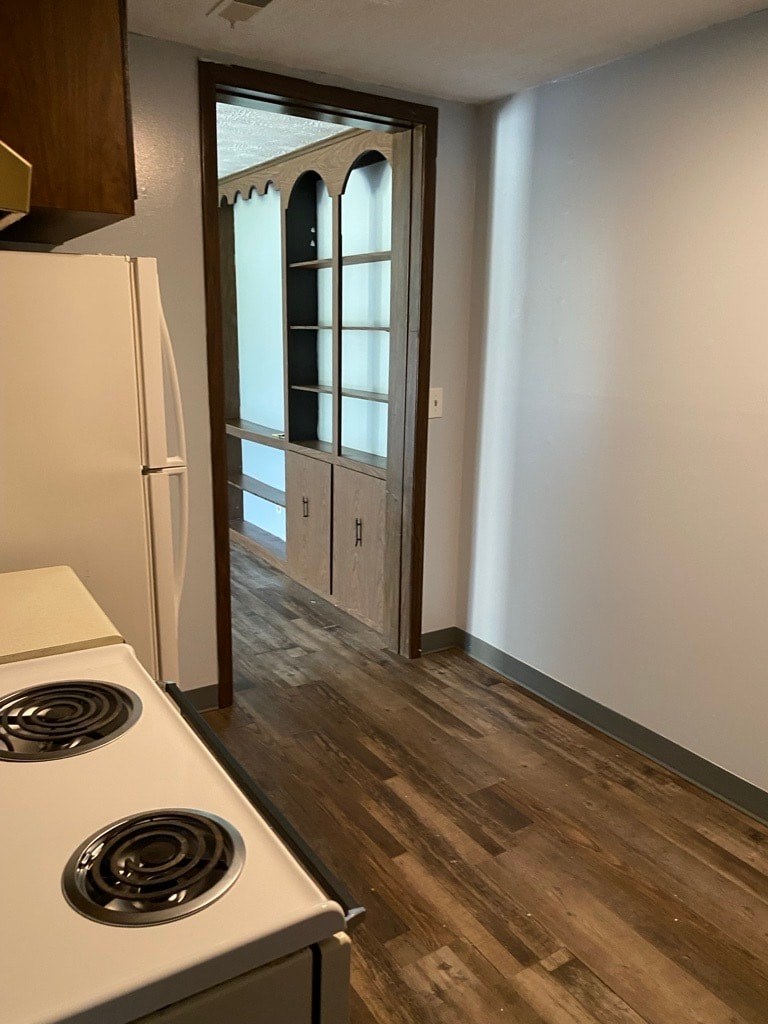 A kitchen with a white stove top oven and a white refrigerator.