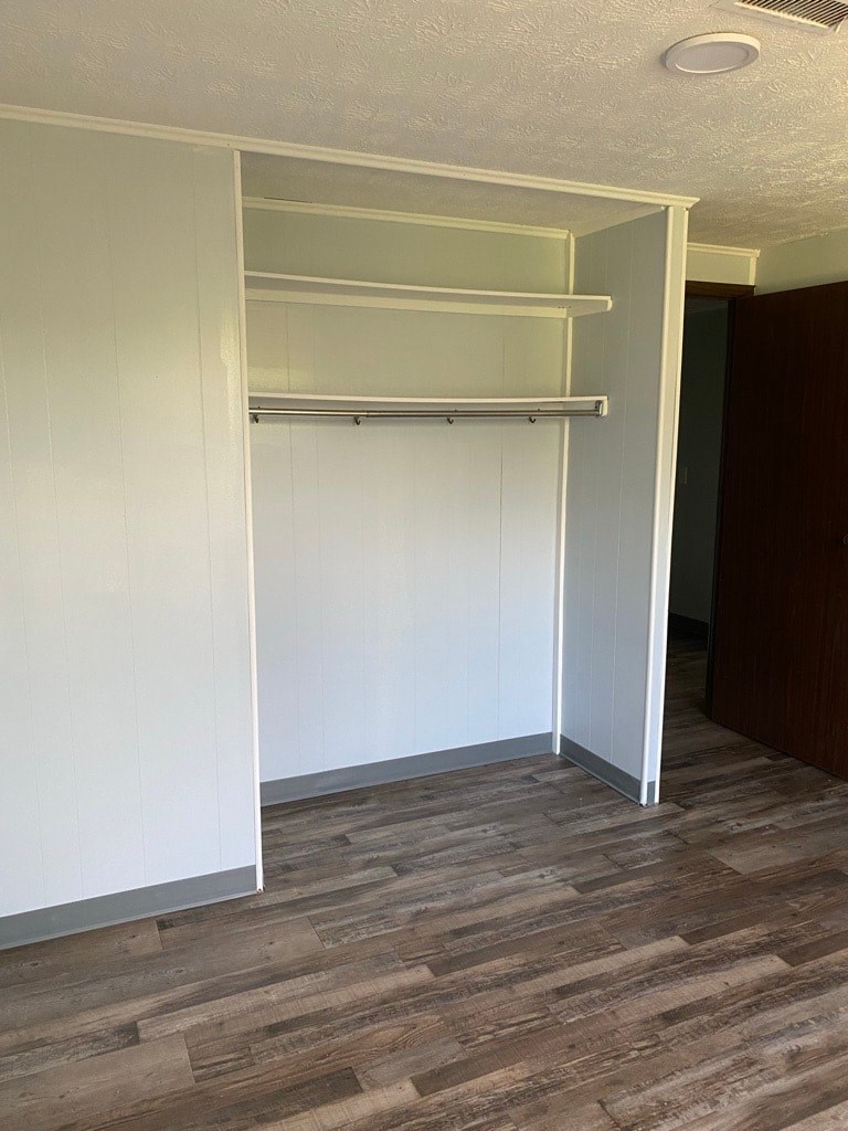 A white closet with a shelf and a wooden floor.