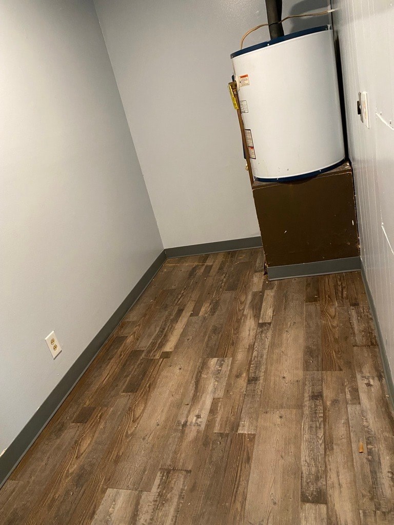 A white refrigerator is in a room with wood flooring.