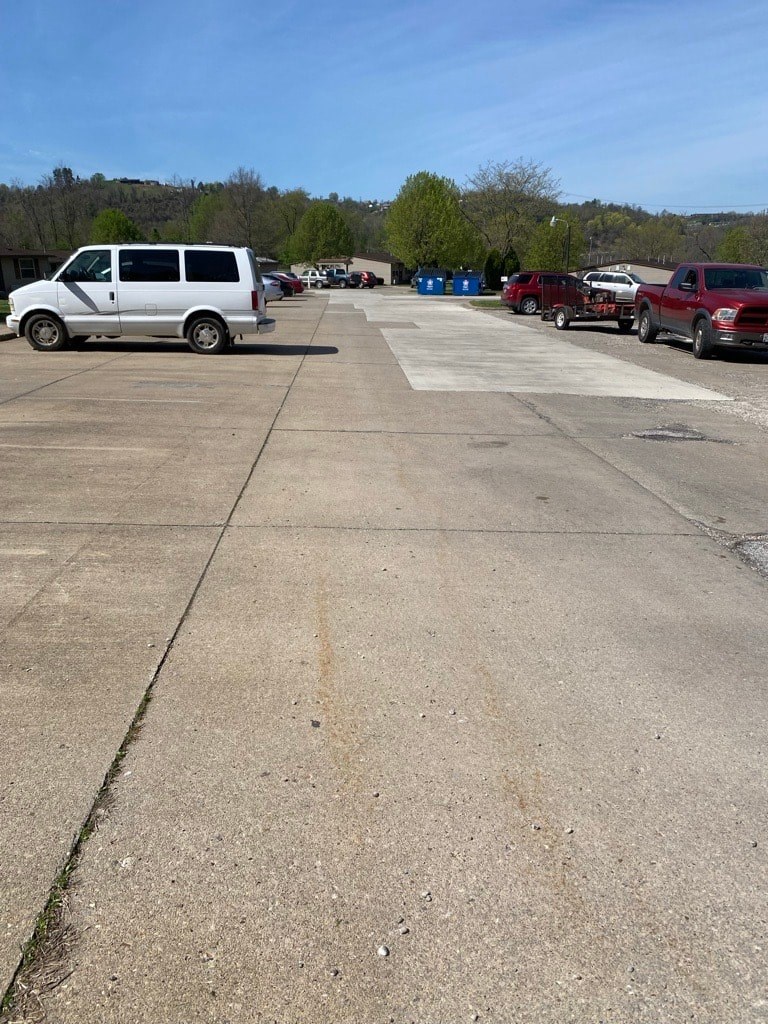 A parking lot with a white van in the foreground and other vehicles in the background.