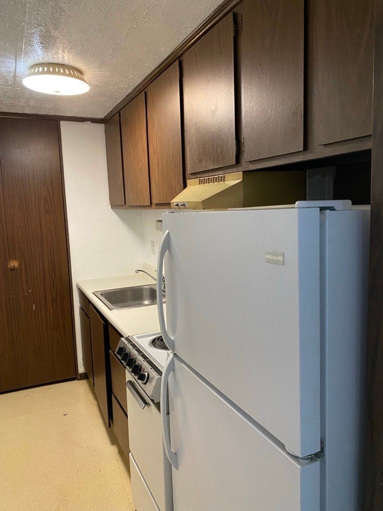 A white refrigerator in a kitchen with wooden cabinets.