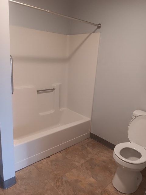 A white toilet is in a bathroom with a walk-in shower.