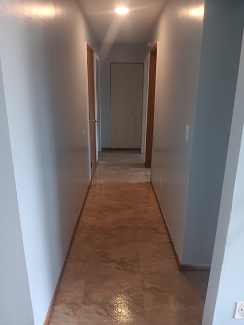 A long hallway with a tan floor and white walls.