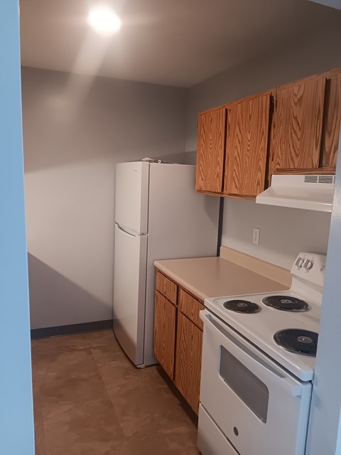 A kitchen with a white refrigerator, white stove, and brown cabinets.